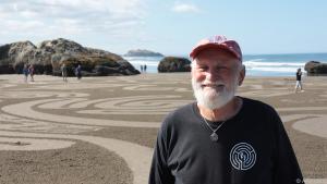 Künstler Denny Dyke malt am Strand seine Sand Circles