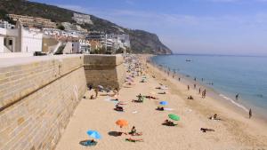 Am Strand von Sesimbra haben es sich ein paar Sonnenhungrige gemütlich gemacht