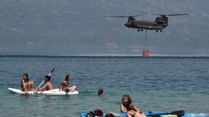Touristen beobachten einen Löschhubschrauber, wie er Wasser aufnimmt