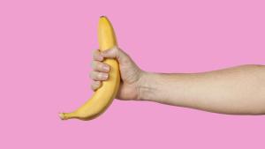 Banana as a symbol of male penis in hand on a yellow background hidden by censorship. Sexual masturbation and orgasm, impotence problem. Self-pleasure concept