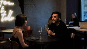 Eine Frau und ein Mann sitzen an einem runden Tisch in einem Restaurant, trinken Wein und unterhalten sich