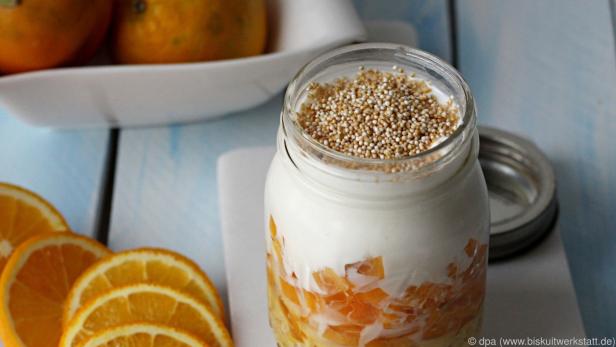 Im Glas werden Haferflocken mit Orangensaft und anderen Zutaten geschichtet