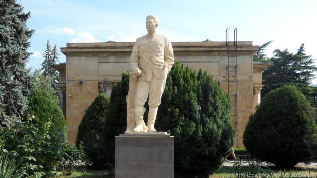 Ein Denkmal von Stalin, dahinter steht sein angebliches Geburtshaus