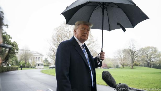 Donald Trump steht im Regen vor dem Weißen Haus