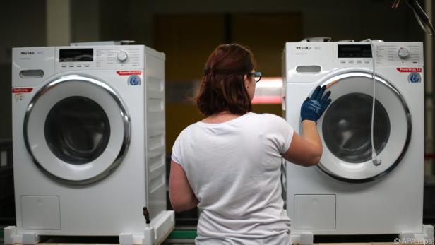 Eine Arbeiterin klebt Aufkleber auf eine Waschmaschine