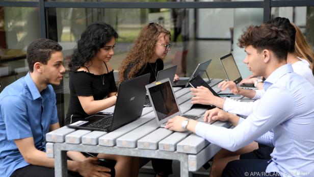 Lehrer pochen neben Laptops auf Infrastruktur für digitale Schule.