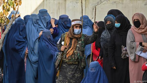 Ein Taliban-Kämpfer bewacht auf der Straße wartende Frauen in Kabul