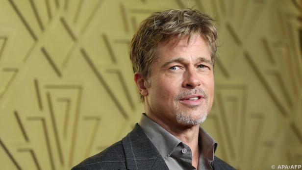 Brad Pitt steht vor einer hellgrünen Wand und blickt in die Kamera