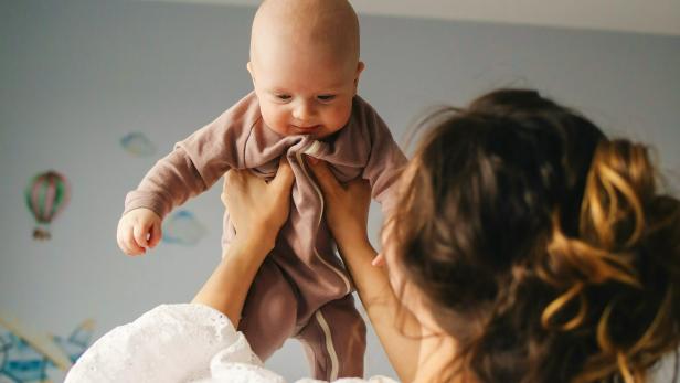 Mutter hebt ein kleines Baby in ihren Händen 