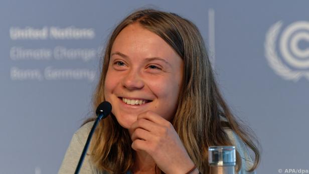 Dunkelblondes 21-jähriges Mädchen sitzt bei einer Pressekonferenz vor ihrem Mikrofon und lächelt