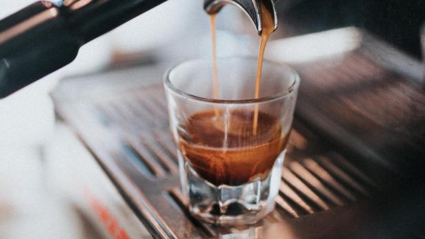 Espresso tröpfelt aus einer Maschine in ein kleines Glas