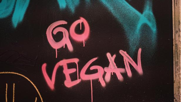 "Go vegan" wurde in roter Schrift an eine schwarze Wand gesprüht