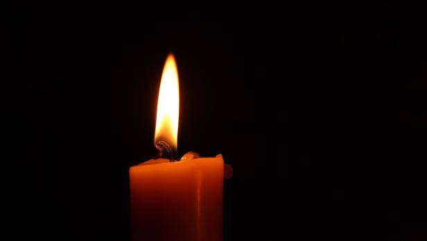 Brennende Kerze vor schwarzem Hintergrund