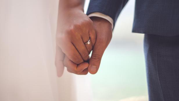 Mann und Frau halten sich an den Händen, die Frau trägt einen Diamantring am Finger