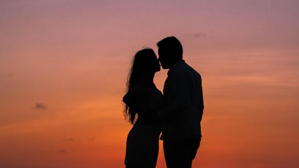 Silhouette eines Paars, das sich im Sonnenuntergang küsst