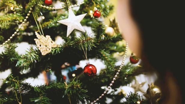 Detailaufnahme eines Weihnachtsbaums mit Christbaumkugeln, Sternen und Kunstschnee