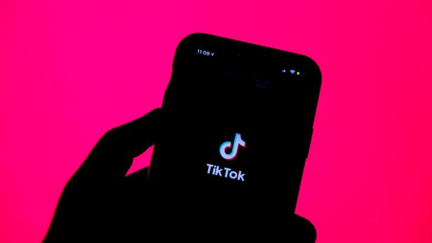 iPhone zeigt TikTok-Logo vor pinkem Hintergrund
