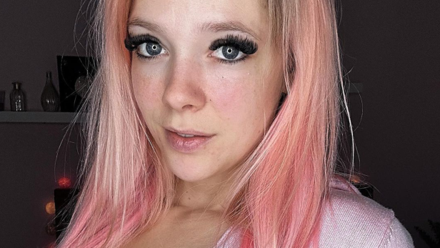 Frau mit rosa Haaren blickt für ein Selfie in die Kamera