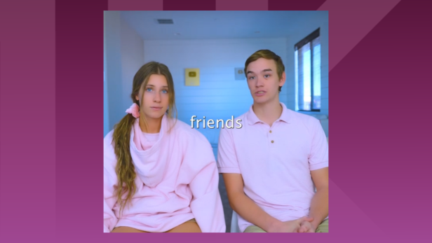 Frau und Mann in rosa Shirts sitzen nebeneinander und blicken ernst in die Kamera