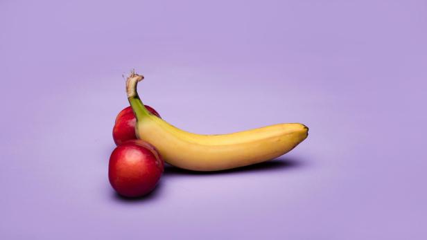 Eine Banane und zwei Pfirsiche auf lila Hintergrund