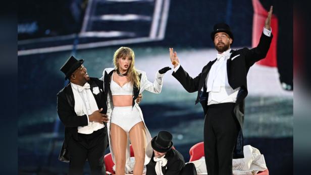 NFL-Superstar Travis Kelce überraschte beim Konzert seine Freundin Taylor Swift auf der Bühne – standesgemäß in Smoking und Zylinder.