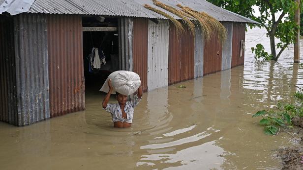 Mann mit Reissack in überfluteter Gegend in Assam