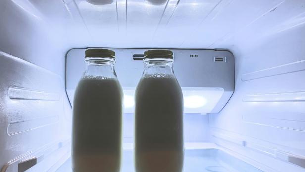 zwei Glasflaschen mit Milch stehen im Kühlschrank